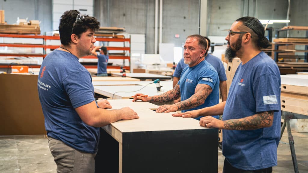 Steadfast Displays fabrication team discussing booth build strategy inside the workshop.