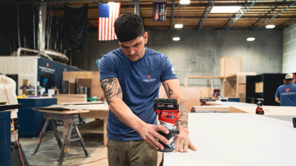 Steadfast Displays team member using a power tool to craft a custom trade show display inside a fabrication warehouse.